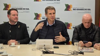 Três homens brancos sentados lado a lado. Há um tablet na frente deles.