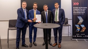 Quatro homens brancos de terno e gravata posam para foto segurando um documento.