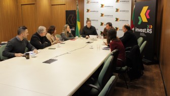 Pessoas conversando sentadas em volta de uma grande mesa de reuni&otilde;es